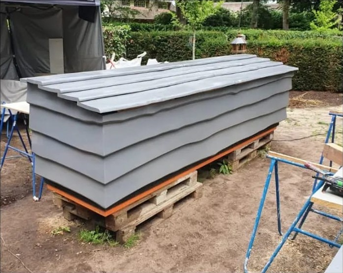 Grijze houten kist met overlappende planken op pallets, tijdens de opbouw
